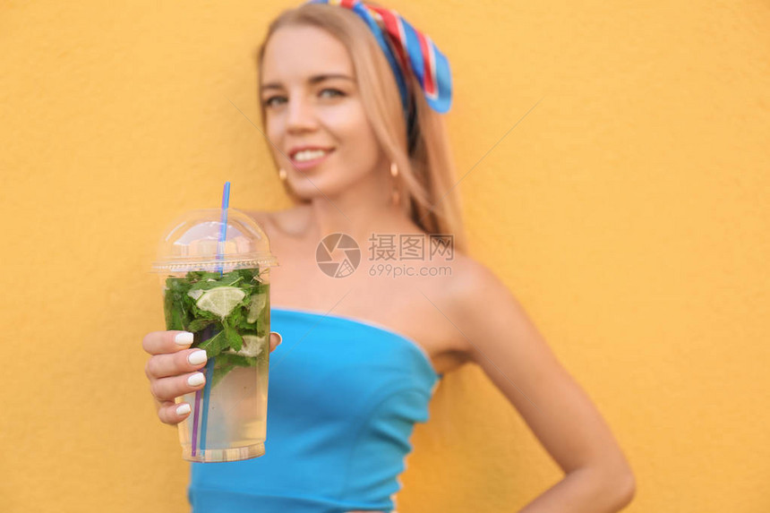 美丽的年轻女子用塑料杯的新鲜鸡尾酒杯图片