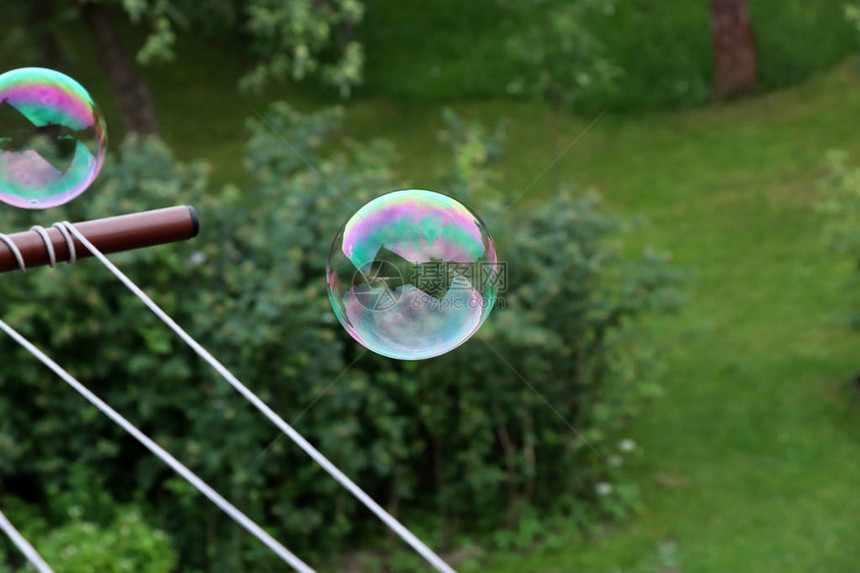 一个五颜六色的泡在花园上方的空中飞舞图片