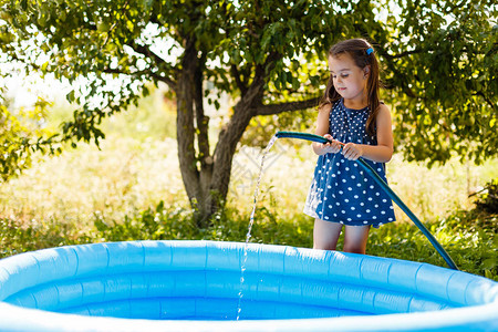 小女孩往充气儿童池里倒水图片