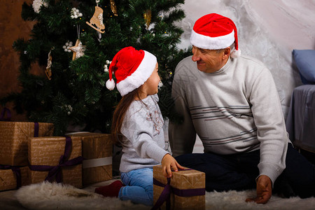 戴着圣诞帽的快乐祖父和孙女坐在装饰精美的圣诞图片