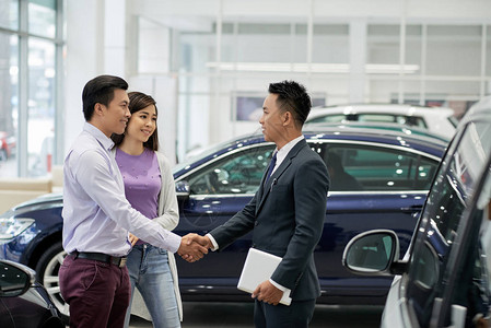 年轻的亚洲青年销售员在汽车经销商中为一背景图片