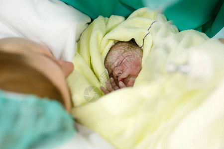 新生儿秒和年轻的母亲和出生后的分钟可爱的小新出生的女婴在毛巾上新生活背景图片