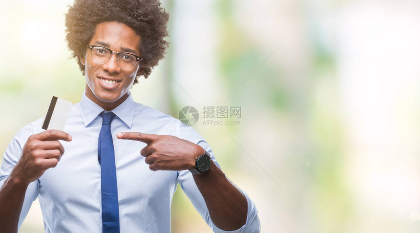 在孤立的背景中持有信用卡的非裔美国人非常快乐地用手和指图片