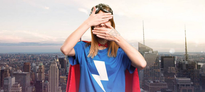 漂亮的超级英雄女孩在摩天大楼的一座城图片