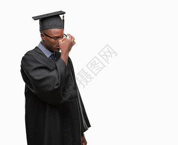 年青的非洲毕业男子在孤立的背景中疲惫地擦鼻子和眼睛图片