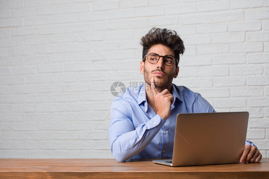 年轻商人坐在笔记本电脑上思考和寻找图片