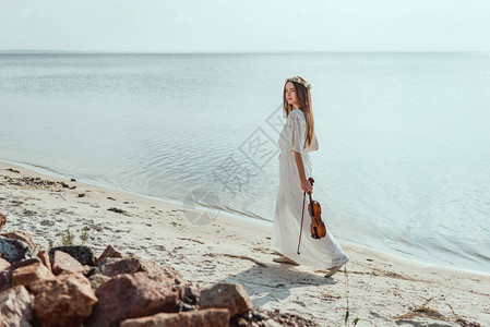 穿着白裙子的美丽优雅佳丽女子拿着小提琴图片