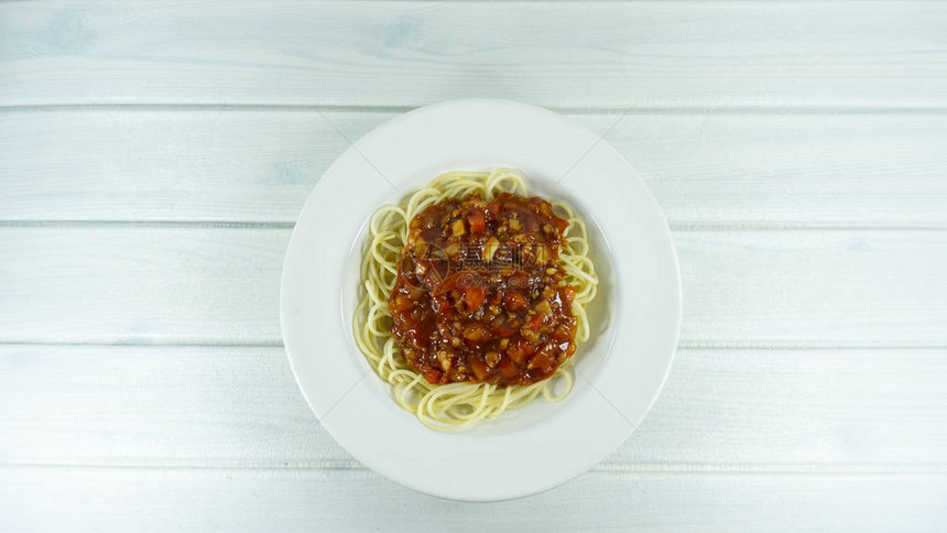 番茄酱和肉的意大利面香肠白色在木质地板桌子上面有复制空图片