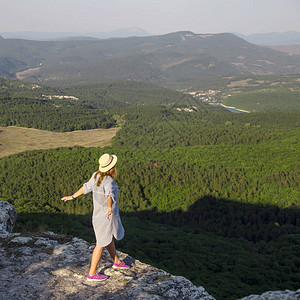少女是站在山崖之上的旅人双臂向前伸展背景图片