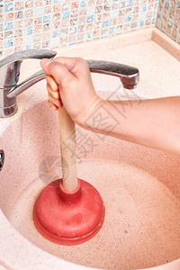 妇女清理厨房的排水池用橡图片