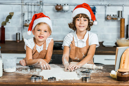 穿着圣塔帽子的可爱快乐孩子准备圣诞节饼干和图片