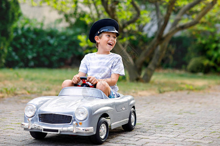 快乐的孩子男孩在夏日花园里玩大旧玩具车图片
