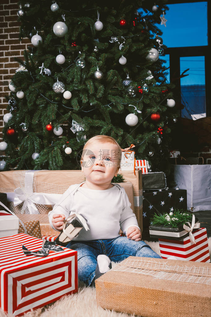 主题冬季和圣诞假期1岁的白种金发男孩坐在圣诞树附近的家地板上图片