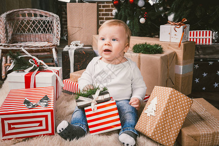 主题冬季和圣诞假期1岁的白种金发男孩坐在圣诞树附近的家地板上图片