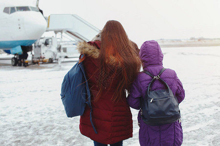 两个背着包的女孩在雪地起降场上登图片