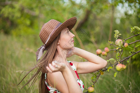 美丽的女孩站在苹果园背景上图片
