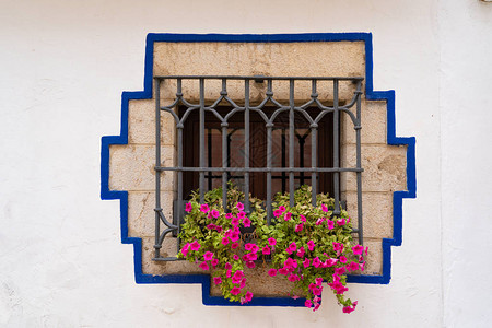 古老的窗户有生锈铁条和在典型的地中海村庄挂花图片