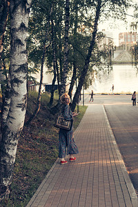 女人沿着路走在河边半转弯的路上在阳光温暖的天图片
