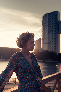 女人站在离河岸附近的木制楼梯上在日落时分的一个城市风景公园图片
