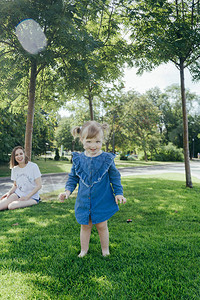 身穿蓝牛仔裤的3岁小女孩穿着蓝色牛仔服在公园走来去图片