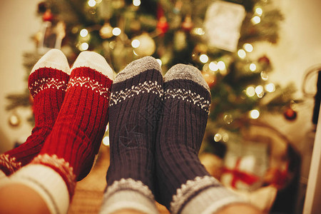 时尚的节日袜子在美丽的圣诞树下的情侣腿上图片