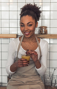 穿着围裙的漂亮非洲裔美国女服务员拿着一杯果汁图片