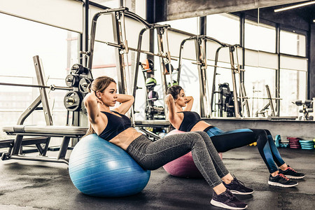 两个可爱的女孩在健身房做体操锻炼做腹部肌图片