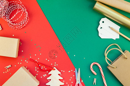 新年或圣诞礼物准备DIY平躺顶视图圣诞假期庆祝手工礼品盒在红绿纸背景贺卡或文本设计的模板背景图片