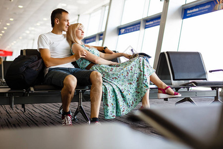 年轻夫妇在机场候机室的椅子上休息图片