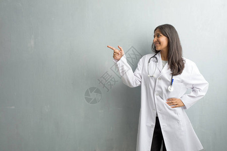 年轻的印度女医生站在一堵墙对面的一边图片