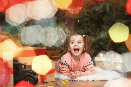 圣诞气氛中的小女孩这个女孩对圣诞节和礼物很满意新年树上的一个图片