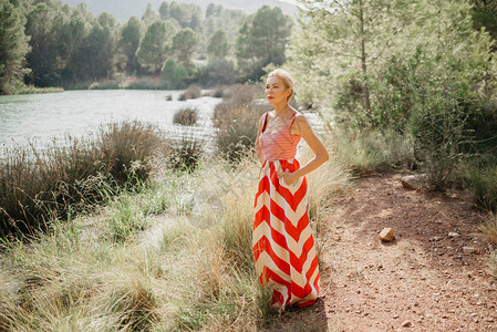 穿红白礼服的时髦金发美女在山湖沼泽处图片