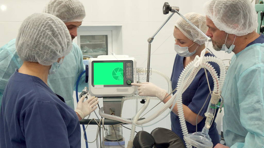 由四名成员组成的外科小组在监视器上讨论某事两名留着胡子的外科医生和两名护士看着屏幕上的绿色度键站立在现代医疗附图片