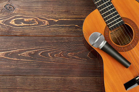 原声吉他与木制背景上的麦克风图片