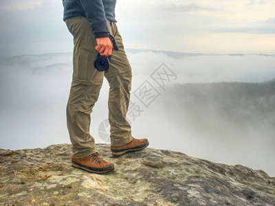 人用照相机双腿膝盖和靴子拍摄岩石高峰的地貌照片图片