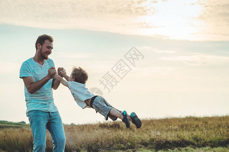 一位年轻的父亲把他的小儿子扔在傍晚的阳光下父亲节父亲抱着他的小儿子图片