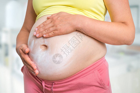 孕妇在肚子上施润湿乳霜皮肤护理和怀图片