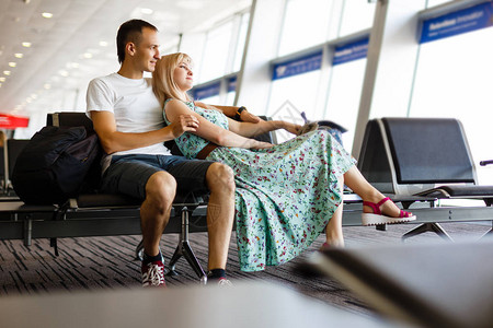 年轻夫妇坐在机场候机室的椅子上等飞机图片