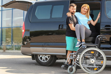 男人帮助残疾妇女坐在轮椅上图片