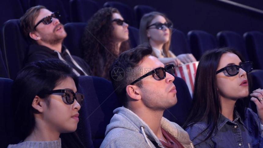 年轻人在电影院享受3D效果观众中的男孩和女孩在电影院抽搐黑发男对电影的特殊视觉图片