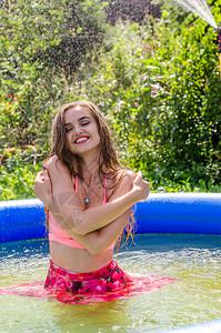 金发美女模特身着优雅的红色泳衣站在泳池中图片