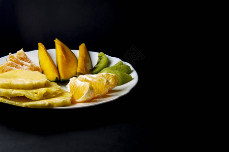 热带水果猕猴桃芒果菠萝橙子和橘子片放在白色盘子上图片