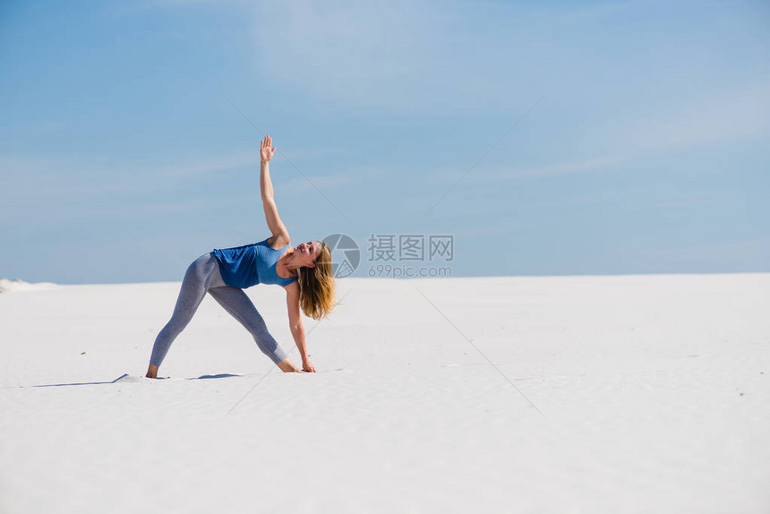 美丽的女教练在沙漠里做三角瑜伽在户外摆出三图片