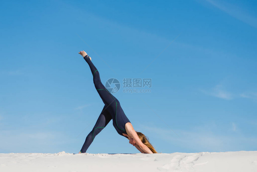 身穿紧身衣的年轻女子在天空和沙图片