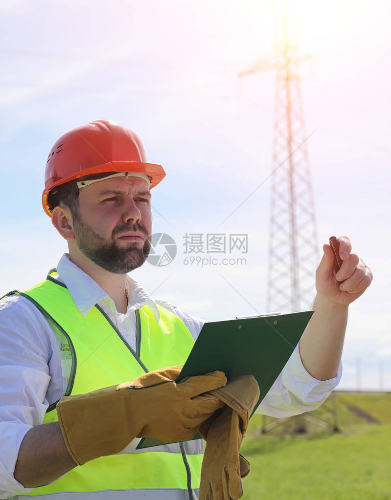 输电线路附近田野里的电工电工管理架设电力线的过程戴着头盔的机械师和反光的形式和特殊图片