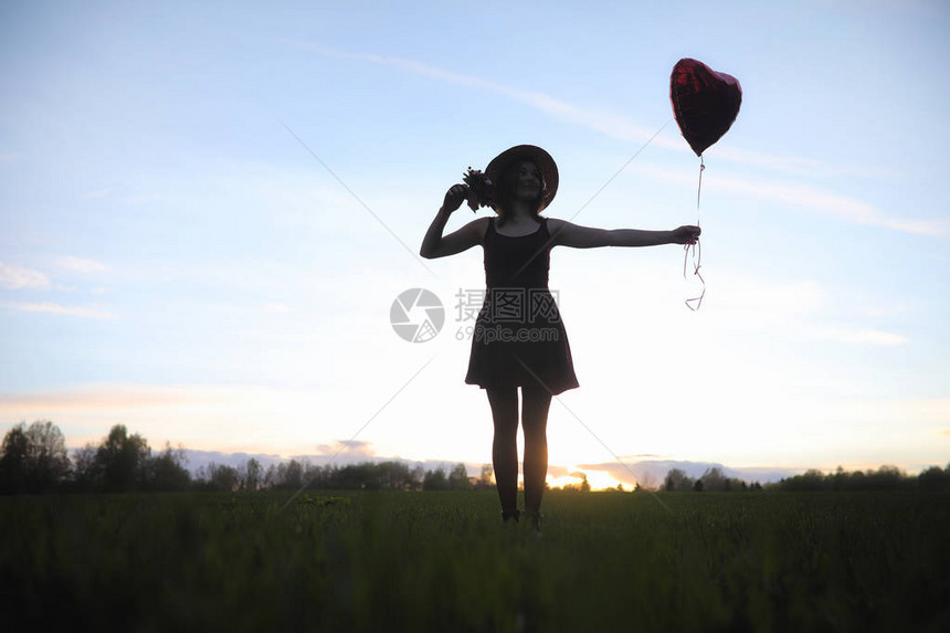 一个戴着帽子的女孩在公园散步一个提着篮子的女孩在春天散步夕阳西下图片