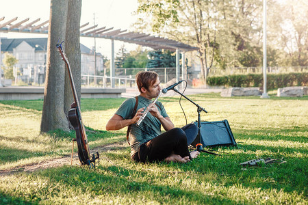 夏天日落时在公园外吹长笛的白人男音乐家的画像图片