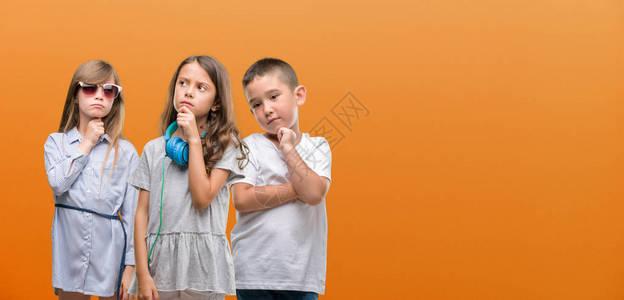 男孩和女孩群体超过橙色背景的孩子严重的面对思考问题图片