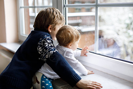 快乐可爱的男孩和可爱的女婴坐在窗边图片