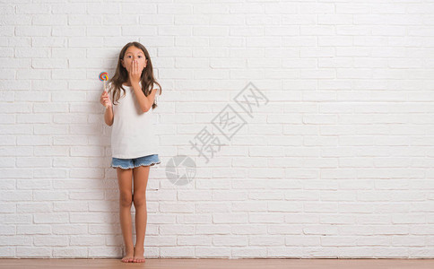 白砖墙上的小黑皮小孩在家中吃棒糖时图片